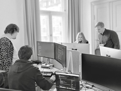 fyra personer som tittar på dataskärmar och pratar
